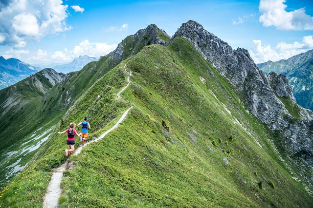 Trail runners near the Col de Balme on the Swiss and French borders, between Trient, Switzerland and Chamonix, France, run a small grassy ridgeline.