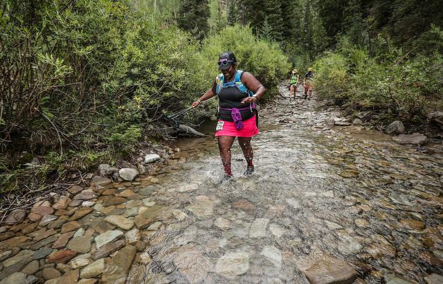 Mirna Valerio running through a river in a trail running race