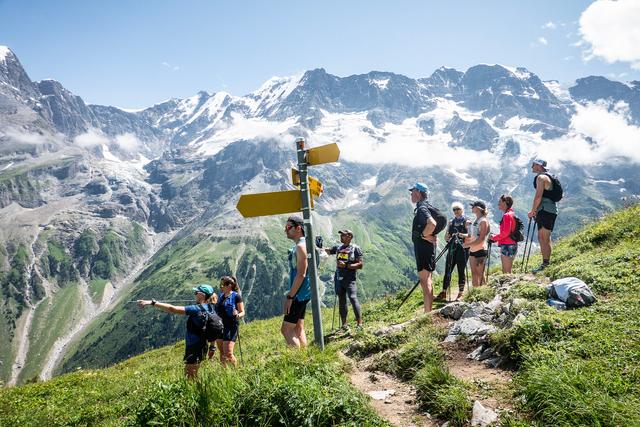 A group of trail runners stopped at a sign post in the Bernese Oberland