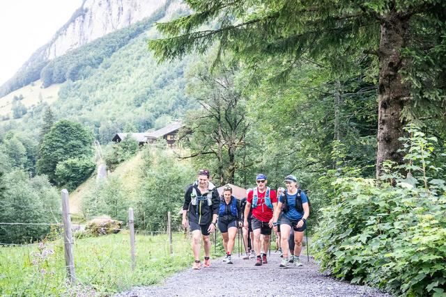 A group of trail runners hiking up a wide trail in the Bernese Oberland
